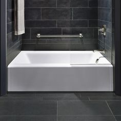 a white bath tub sitting inside of a bathroom next to a shower head mounted on a wall