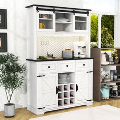 a kitchen with white cupboards and black counter tops next to a potted plant