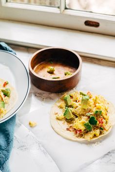 two tortillas on a plate next to a bowl of salsa and a wooden spoon