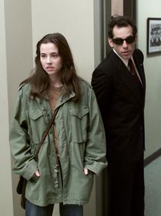 two people standing next to each other in an office hallway