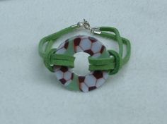 a green and white bracelet with a soccer ball charm on it's end loop