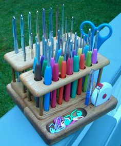 there are many different colored scissors in the holder on the table and one is holding several pairs of scissors