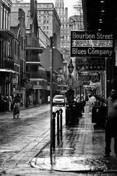 black and white photograph of people walking down the street in an old city with tall buildings