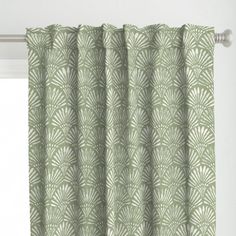 a green curtain hanging on the side of a window in front of a white wall