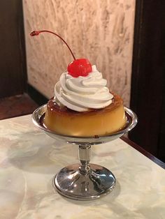 a dessert with whipped cream and a cherry on top is sitting on a silver platter