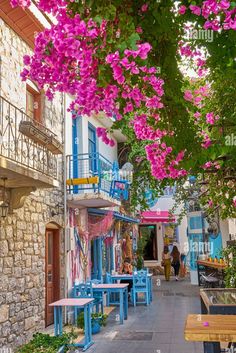 an alleyway with tables and flowers in the foreground