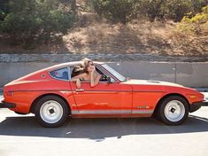 a woman is sitting in the driver's seat of an orange car