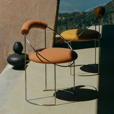 two chairs sitting next to each other on top of a cement slab with mountains in the background