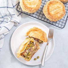 a white plate topped with a piece of pie next to two other pies on cooling racks