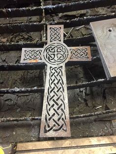 a metal cross sitting on top of a wooden floor next to other tools and materials