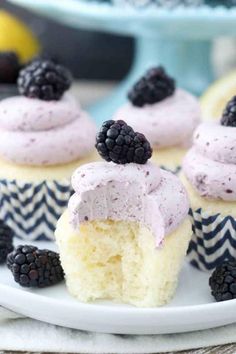 some cupcakes with frosting and blackberries on top are sitting on a plate