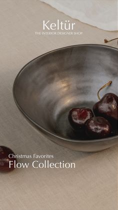 a metal bowl filled with cherries on top of a table