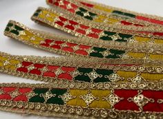 several different colored bracelets are lined up together on a white surface with gold trimming