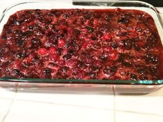 a glass casserole dish filled with fruit on top of a white tiled counter