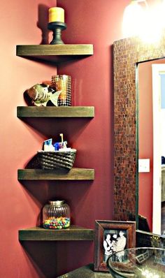 a bathroom with three wooden shelves on the wall and a mirror in the corner behind it