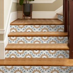 a stair case with blue and white tiles on the bottom, next to a potted plant