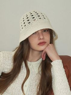 a woman sitting in a chair wearing a white knitted hat with crochet