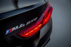 the rear end of a black car with red brake lights and bmw logo on it