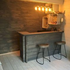 an empty bar with two stools in front of it and some lights hanging from the ceiling