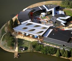 an aerial view of a large building next to a body of water with trees in the foreground