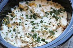 a crock pot filled with pasta and cheese covered in parsley on the side