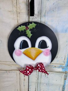 a black and white penguin with a red bow on it's head hanging from a door