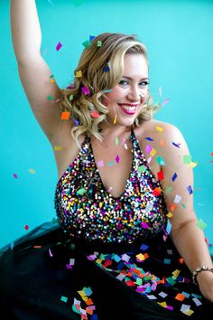 a woman in a black dress with colorful confetti on her head and arms