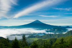 a mountain covered in clouds and surrounded by trees