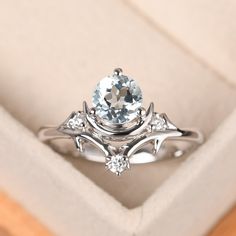 a ring with an aqua blue topaz surrounded by white diamonds in a gift box