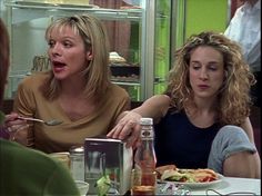 three women sitting at a table with food in front of them and one woman holding a napkin