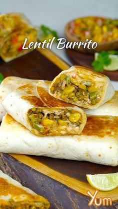 two burritos are sitting on a cutting board with lime wedges and cilantro