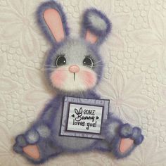 a stuffed animal rabbit holding a sign that says some bunny loves you on it's chest