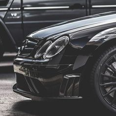 the front end of a black car parked next to other cars