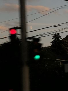 the traffic light is red and green at night time, with power lines in the background