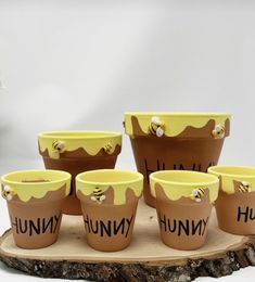 six flower pots with bees painted on them sitting on a wooden tray next to each other