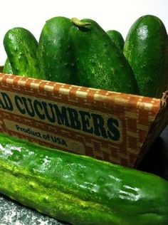 cucumbers are sitting in a cardboard box on a counter next to each other