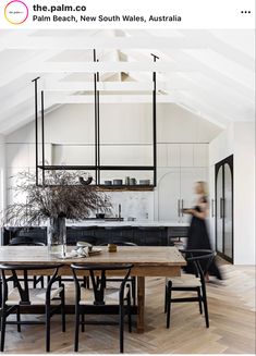 an open kitchen and dining room with white walls, wood floors and ceiling beams is featured in this magazine