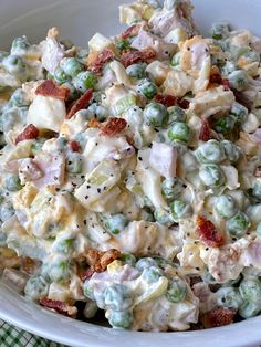 a white bowl filled with pasta salad on top of a green and white checkered table cloth