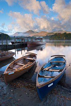 two boats sitting on the shore next to each other