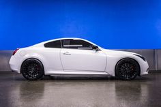 the white sports car is parked in front of a blue wall with black rims