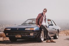 a man leaning on the hood of a car