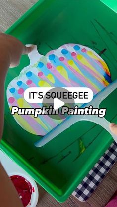 a child is painting a cake in a green box with the words it's squeezee pumpkin painting on it