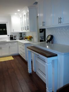 a kitchen with white cabinets and wood flooring, along with an island in the middle