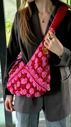 a woman is holding a pink crocheted purse