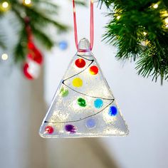 a glass ornament hanging from a christmas tree with colored lights on it's side