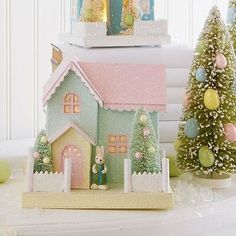 two small christmas trees are next to a doll house