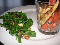 carrots, green beans and other vegetables on a plate next to a glass of water