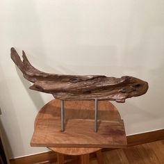 a piece of wood sitting on top of a wooden table next to a white wall