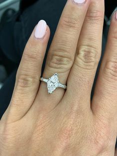 a close up of a person's hand with a diamond ring on their finger