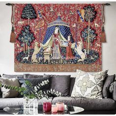 a tapestry hanging on the wall above a couch in front of a table with candles